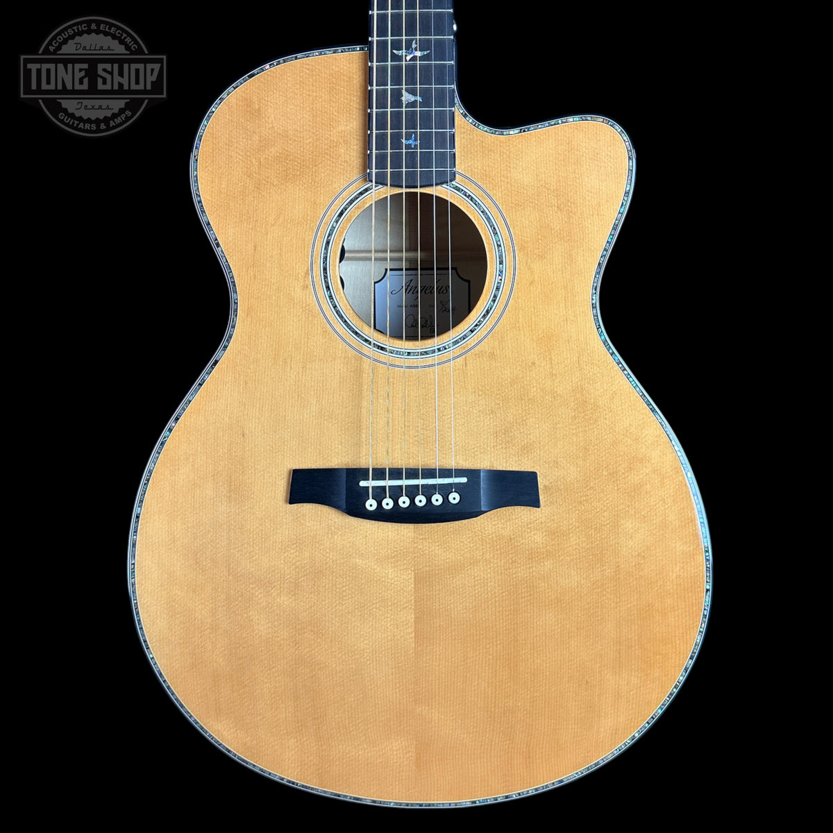 A cutaway acoustic guitar with a natural wood finish and black pickguard, shown against a solid black background with a Tone Shop watermark in the top left corner.