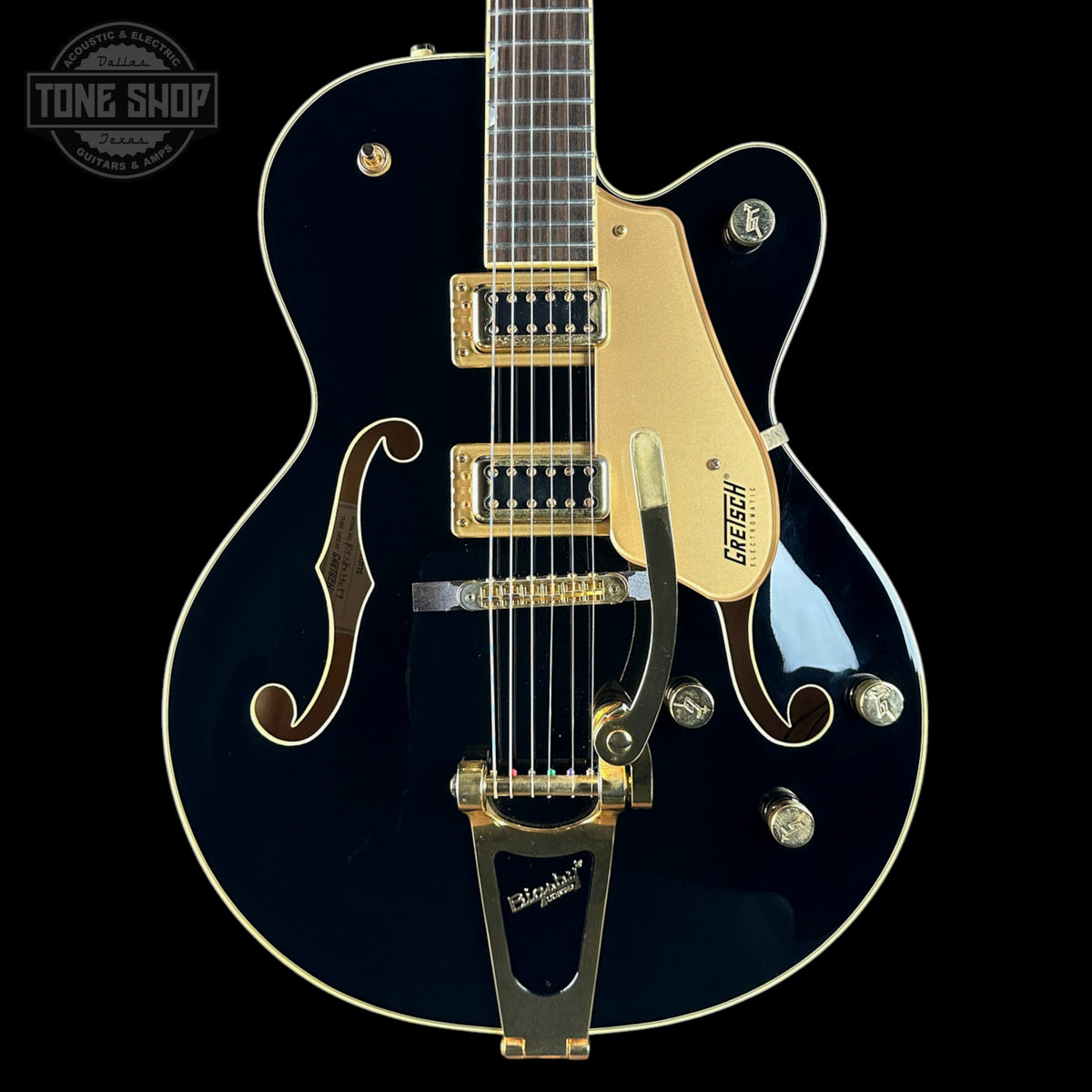 Gretsch electric guitar with a black finish and gold hardware on a black background.