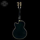 Back view of a black electric guitar with 'Tone Shop' logo in the corner.