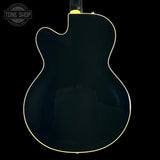 Back view of a black electric guitar with 'Tone Shop' logo.