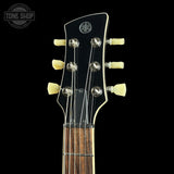 Close-up of a Yamaha electric guitar headstock with six cream-colored tuning keys and silver tuning pegs on a black background.