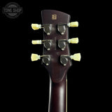 Close-up rear view of a guitar headstock with six cream-colored tuning pegs and a dark reddish-brown wood finish, shown against a solid black background. A Tone Shop watermark is visible in the top-left corner.