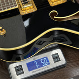 Black electric guitar on a digital scale displaying weight