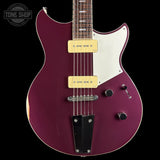 A purple electric guitar with a white pickguard and gold humbucker pickups, shown against a black background with a Tone Shop watermark in the top left corner.