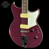A burgundy electric guitar with a white pickguard and gold humbucker pickups, shown against a solid black background with a Tone Shop watermark in the top left corner.