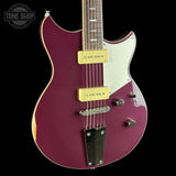 A purple electric guitar with a white pickguard and gold humbucker pickups, shown against a black background with a Tone Shop watermark in the top left corner.