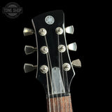 Close-up of a Yamaha acoustic guitar headstock with six silver tuning pegs and strings against a black background.
