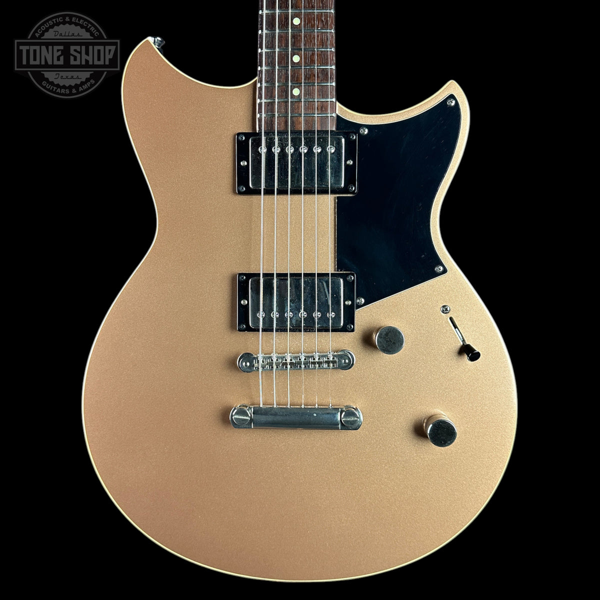 A gold-finish electric guitar with a black pickguard and chrome hardware, shown against a solid black background with a Tone Shop watermark in the top-left corner.