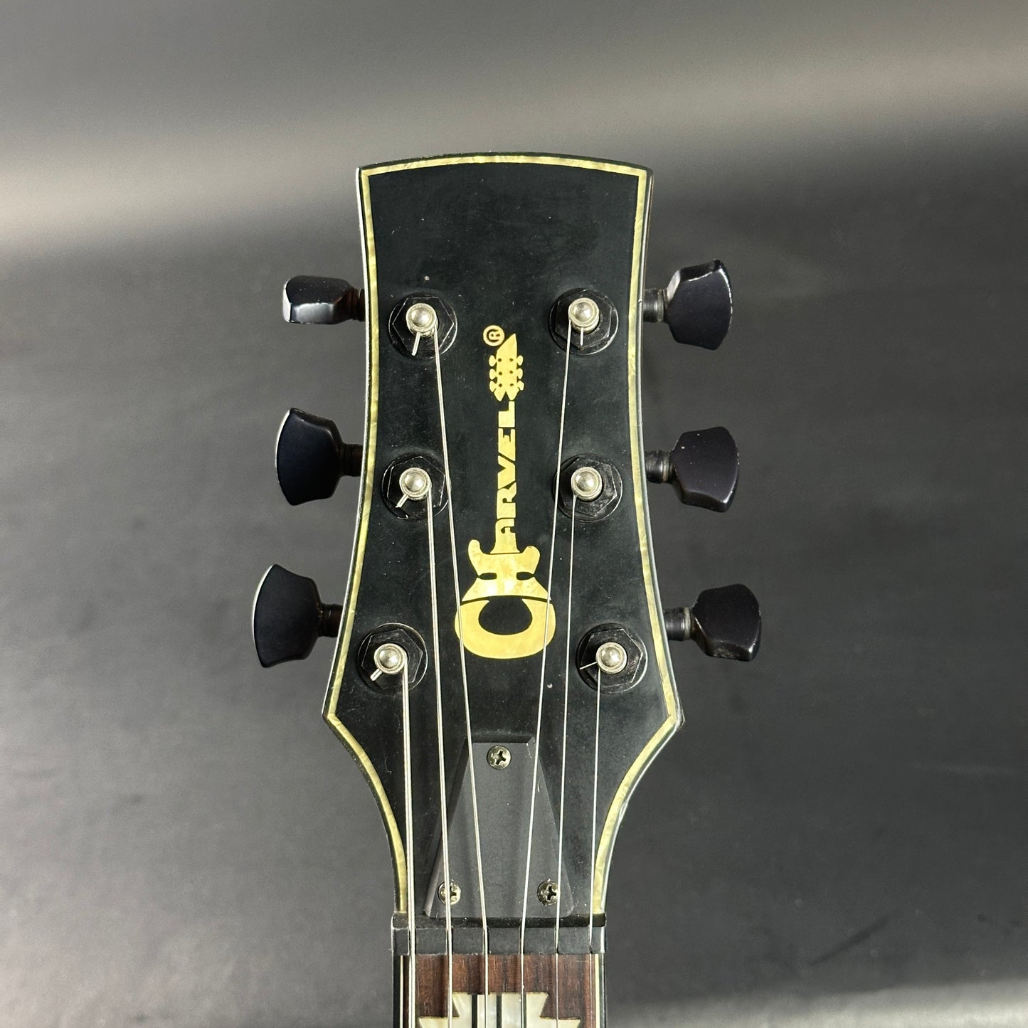 Guitar headstock with brand logo on a gray background