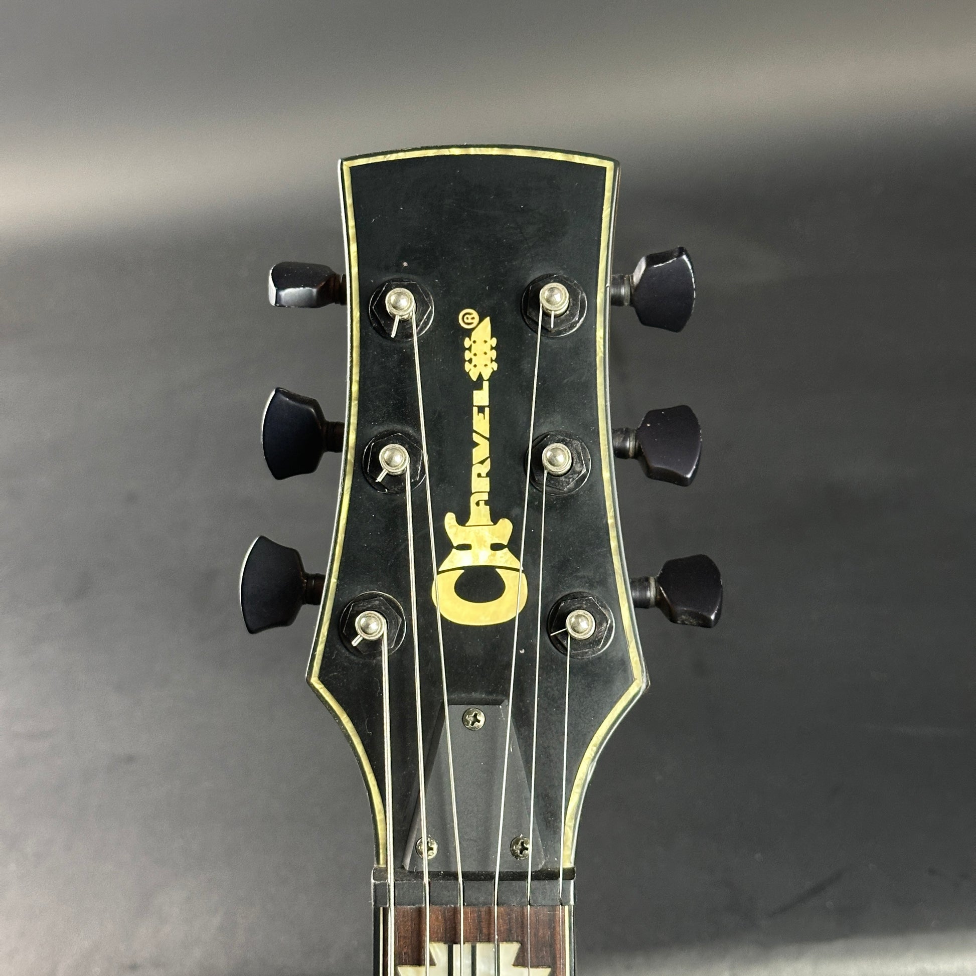 Guitar headstock with brand logo on a gray background
