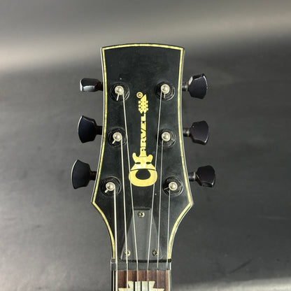 Guitar headstock with brand logo on a gray background