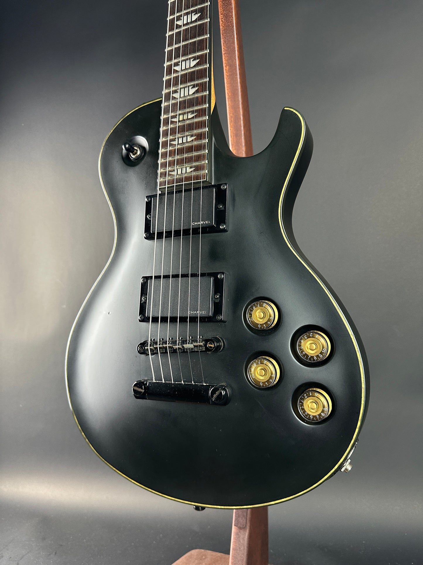 Black electric guitar with gold hardware on a gray background