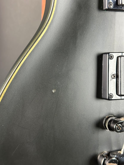 Close-up of a guitar's body with control knobs and tuning pegs.