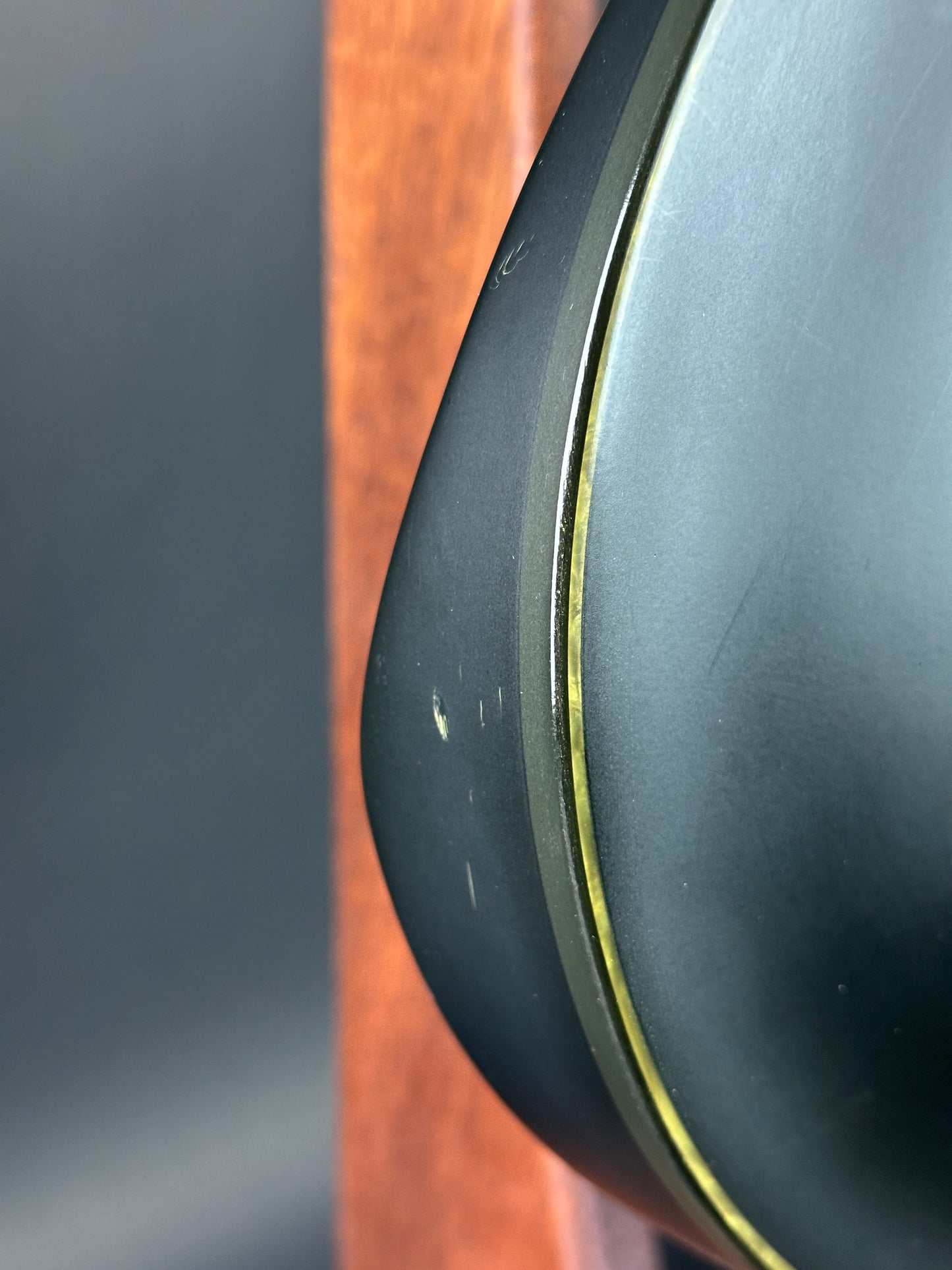Close-up of a black object with a gold rim on a wooden surface