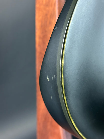 Close-up of a black object with a gold rim on a wooden surface