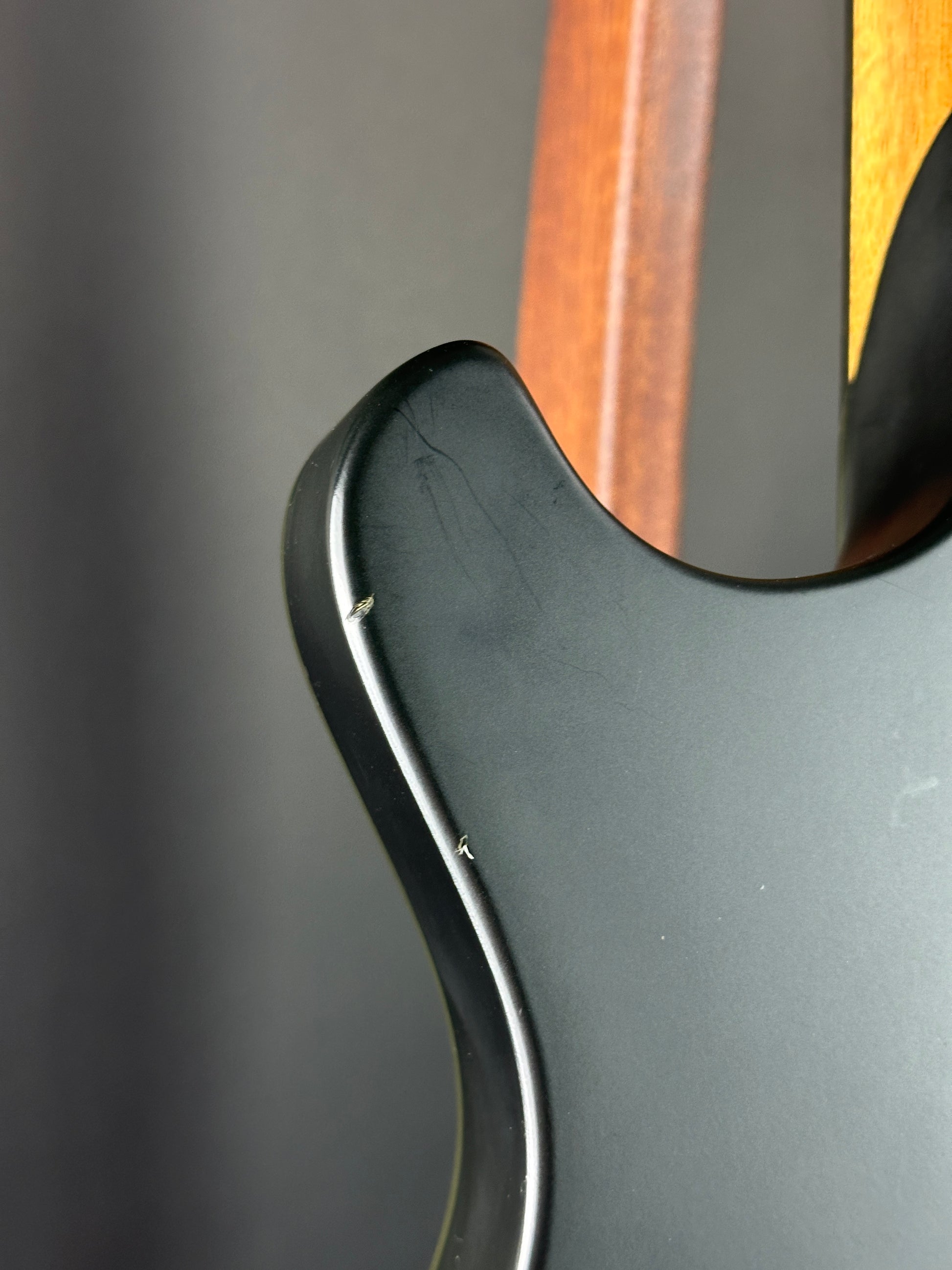 Close-up of a guitar's neck and headstock with a dark background