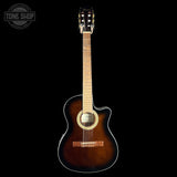 A classical acoustic guitar with a cutaway body, featuring a dark brown sunburst finish, a light wood neck, and a black headstock, shown against a solid black background with a Tone Shop watermark in the top-left corner.