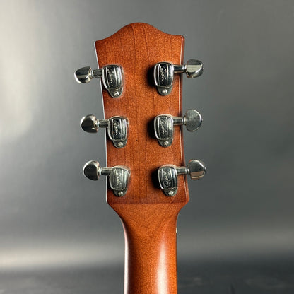 Close-up of a guitar headstock with tuning pegs on a gray background