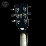 Close-up of a guitar headstock with tuning pegs on a black background, featuring the Tone Shop logo.