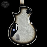 Close-up of a guitar body with a visible brand logo on a black background