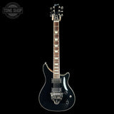 A black electric guitar with chrome hardware and a dark wood fretboard, shown vertically against a solid black background. A Tone Shop watermark is visible in the top-left corner.