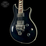 A glossy black electric guitar with chrome hardware, a white edge trim, and a dark wood fretboard, shown against a solid black background with a Tone Shop watermark in the top left corner.