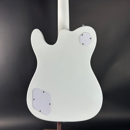 White electric guitar body on a stand against a dark background