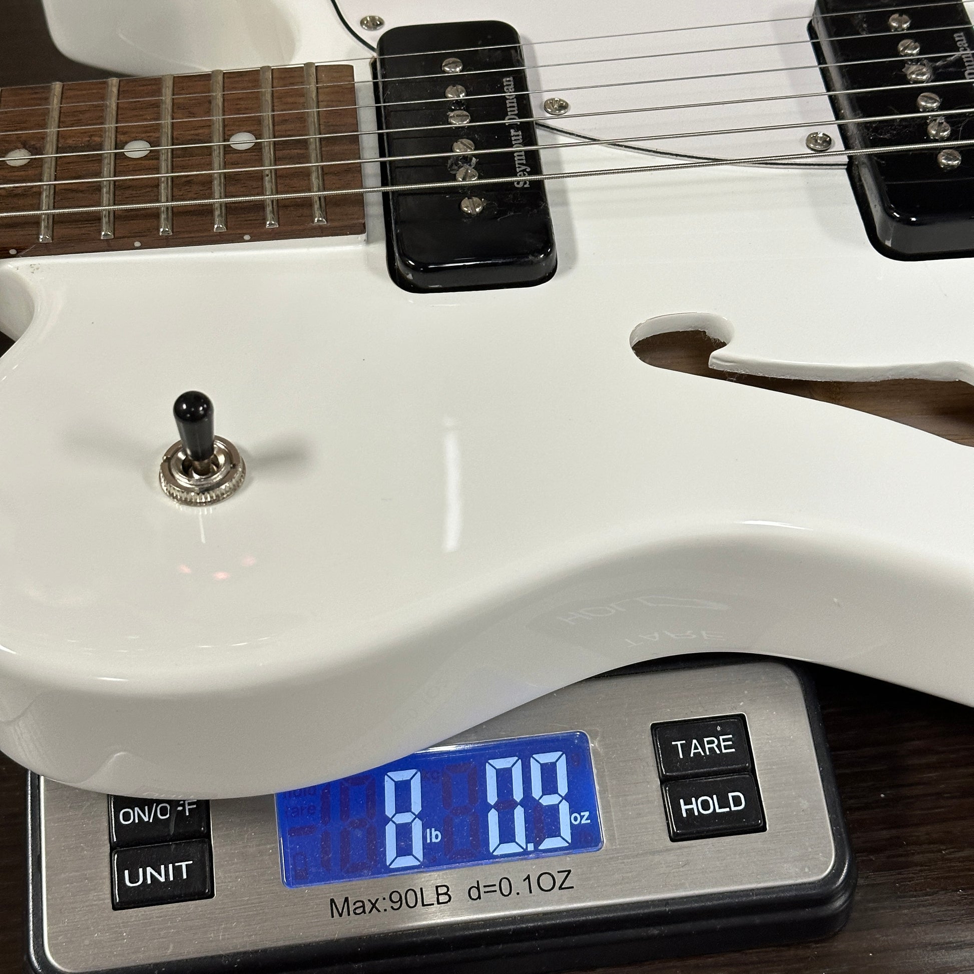 White electric guitar on a digital scale displaying weight