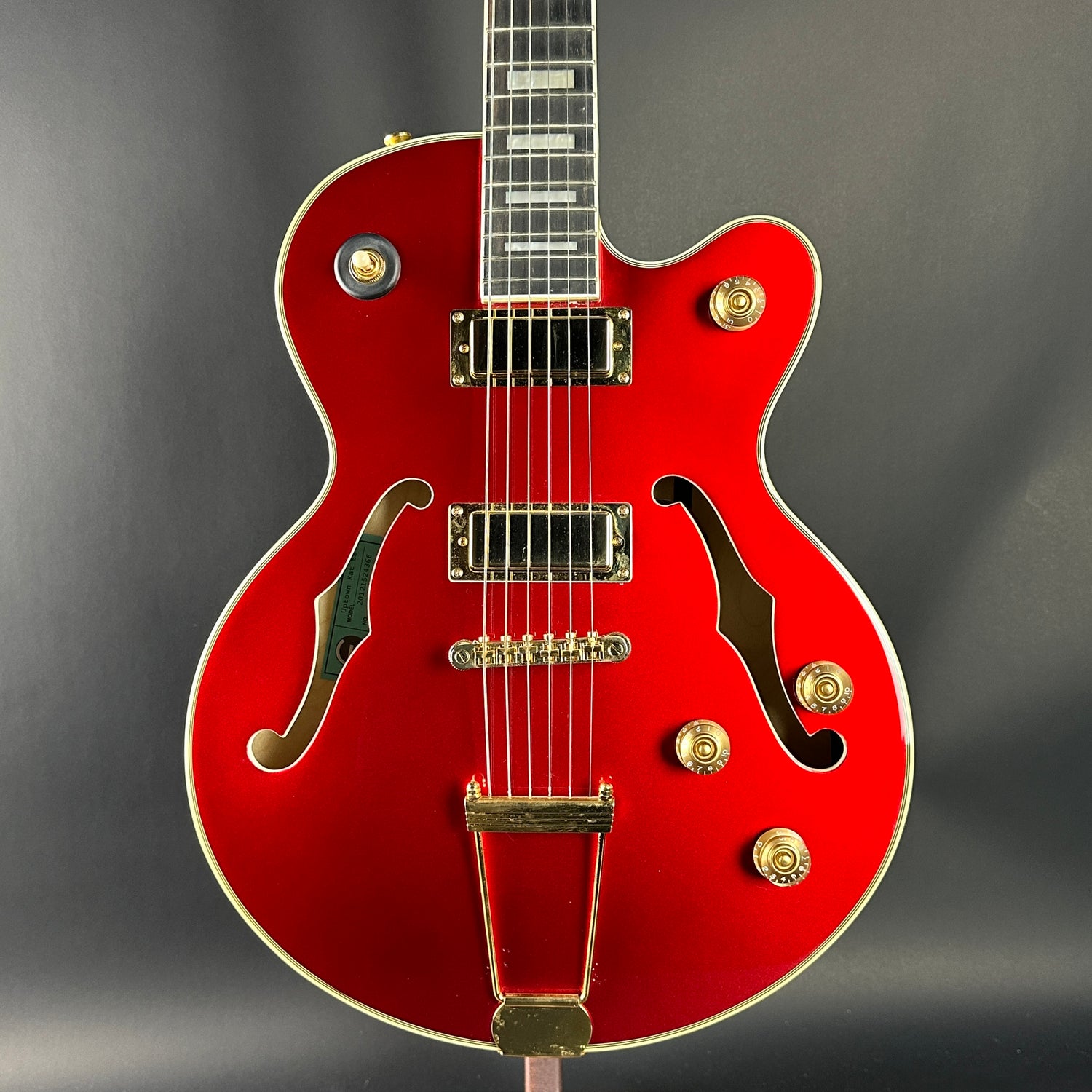 Red electric guitar with gold hardware on a gray background