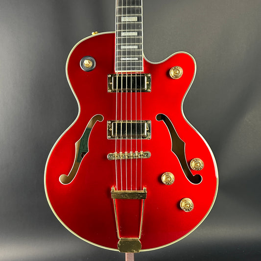 Red electric guitar with gold hardware on a gray background