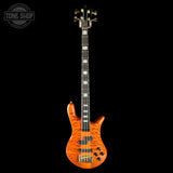 A four-string bass guitar with a vibrant orange flame maple body, black neck, and gold hardware, shown against a solid black background with a Tone Shop logo in the top left corner.