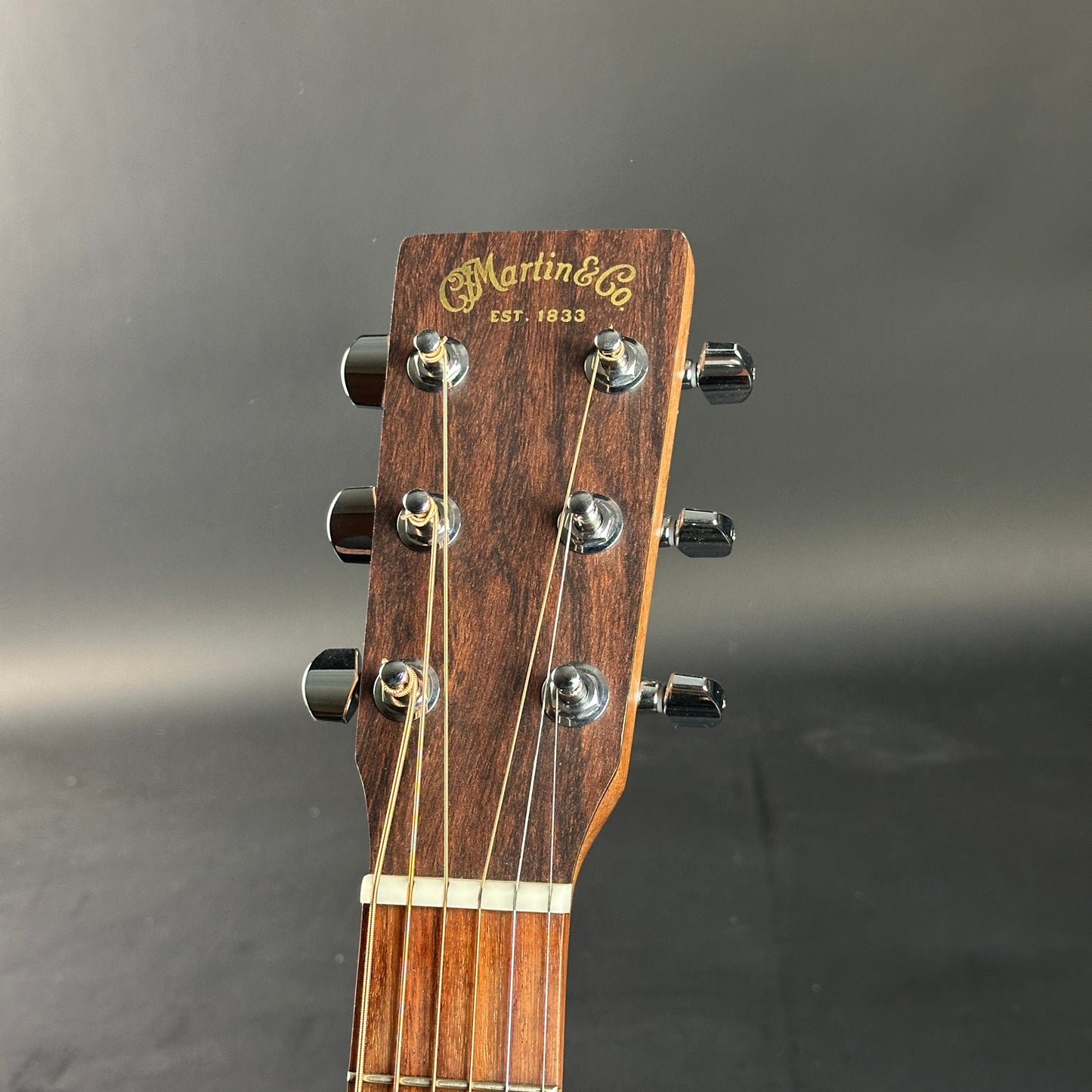 Close-up of a Martin guitar headstock on a gray background