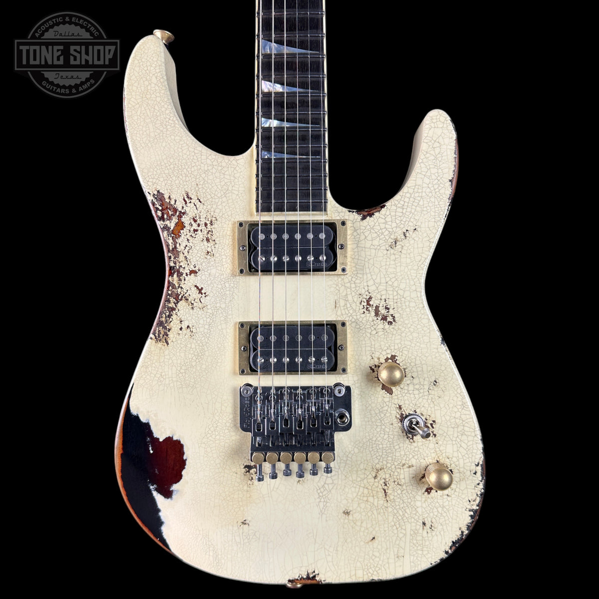 Distressed electric guitar with a white finish and visible wear on a black background.