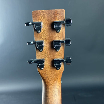 Close-up of a guitar headstock with tuning pegs on a gray background