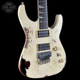 Distressed electric guitar with a white finish and visible wear on a black background.