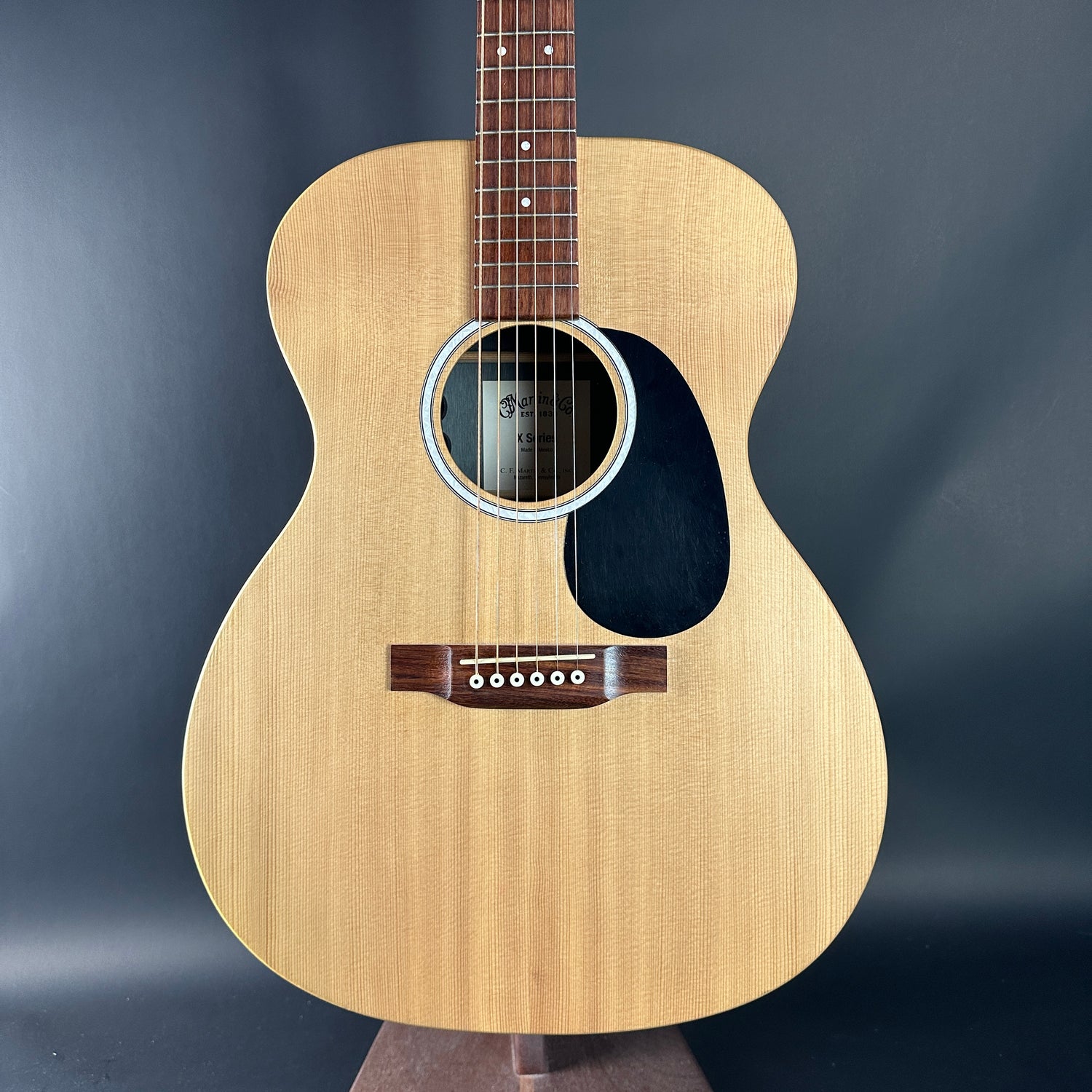 Acoustic guitar with a wooden body and brown neck on a dark gray background