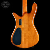 The back of an electric guitar with a glossy natural wood finish, featuring a black pickguard and a black rectangular pickup, shown against a solid black background.