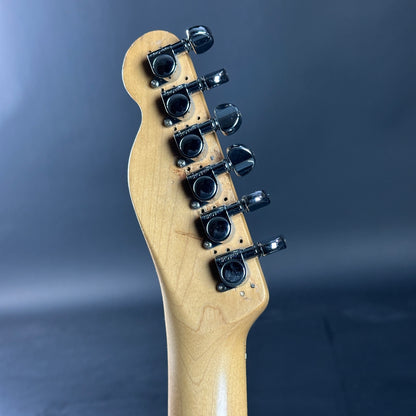 Guitar headstock with tuning pegs on a dark blue background