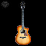 A Taylor acoustic-electric guitar with a natural sunburst finish, shown from the front against a solid black background. The brand logo is visible on the headstock, and a 'TONE SHOP' watermark is in the top-left corner.