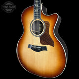 A Taylor acoustic-electric guitar with a natural sunburst finish, shown from a front three-quarter angle against a solid black background. The brand logo 'TONE SHOP' is visible as an overlay in the top-left corner.