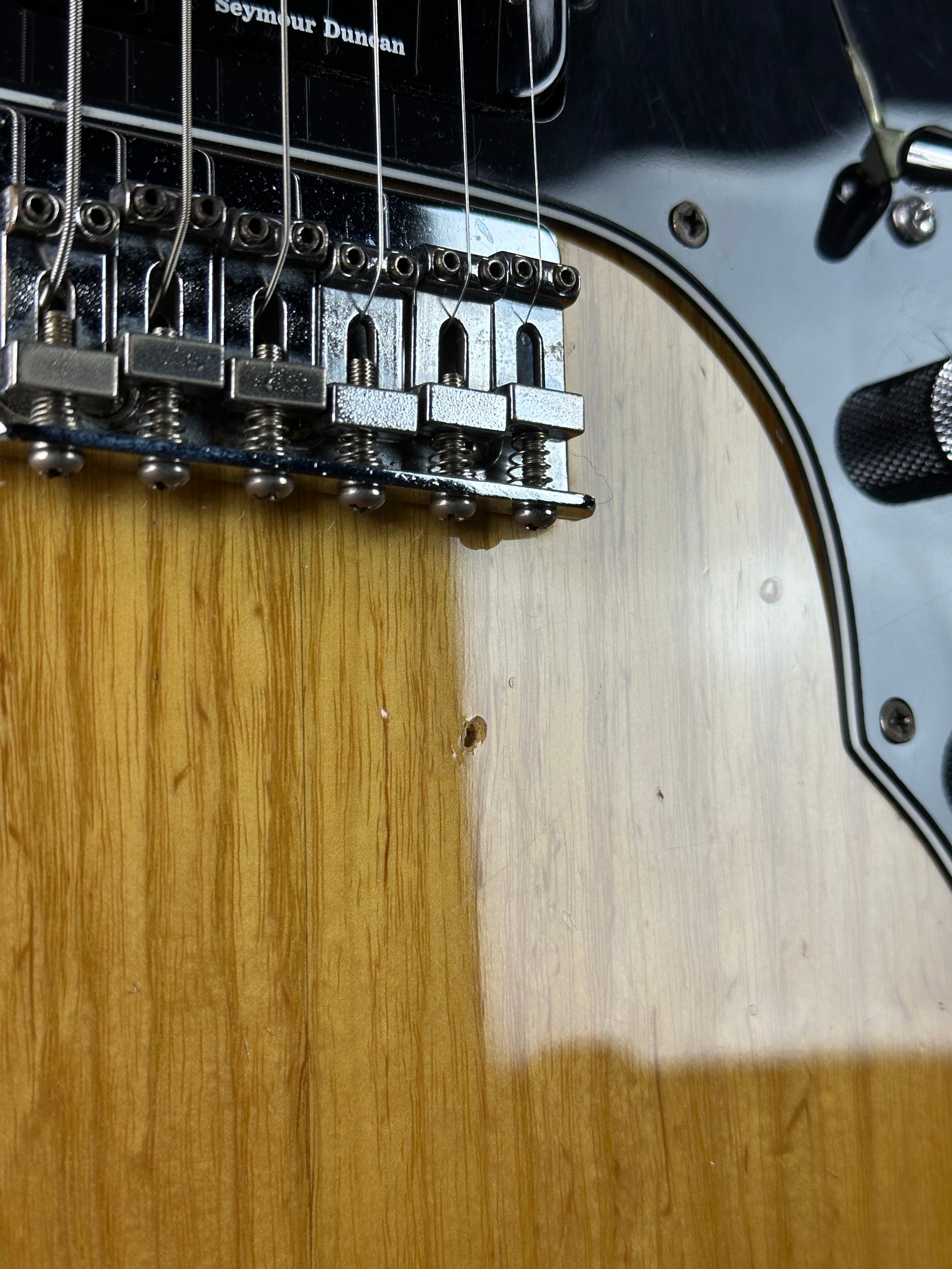 Close-up of a guitar's headstock and tuning pegs on a wooden surface