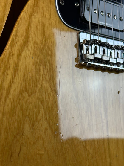 Close-up of a guitar's neck and headstock on a wooden surface