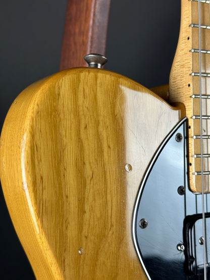 Close-up of a guitar's wooden body and headstock on a dark background