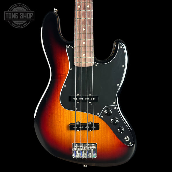 A classic four-string electric bass guitar with a sunburst finish, featuring a black pickguard and control knobs, shown against a solid black background with a Tone Shop watermark in the top left corner.