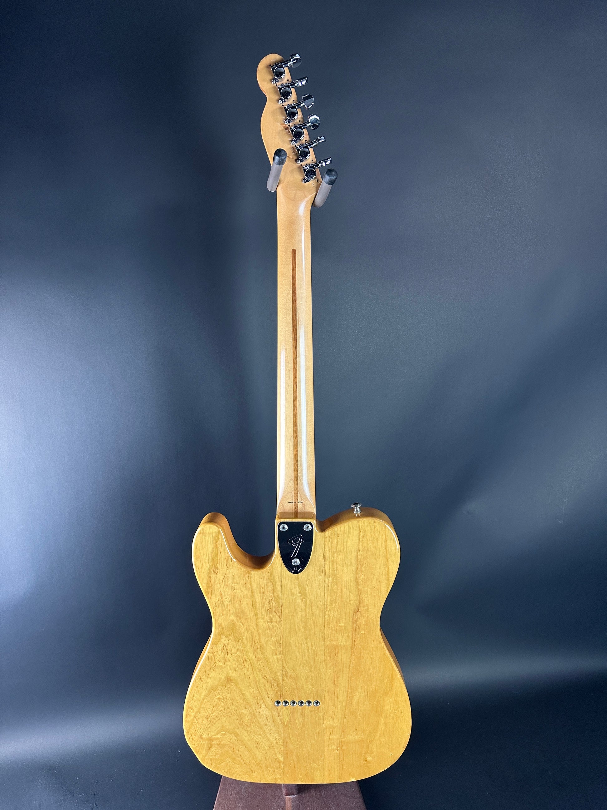 Electric guitar with a wooden body and neck on a dark blue background