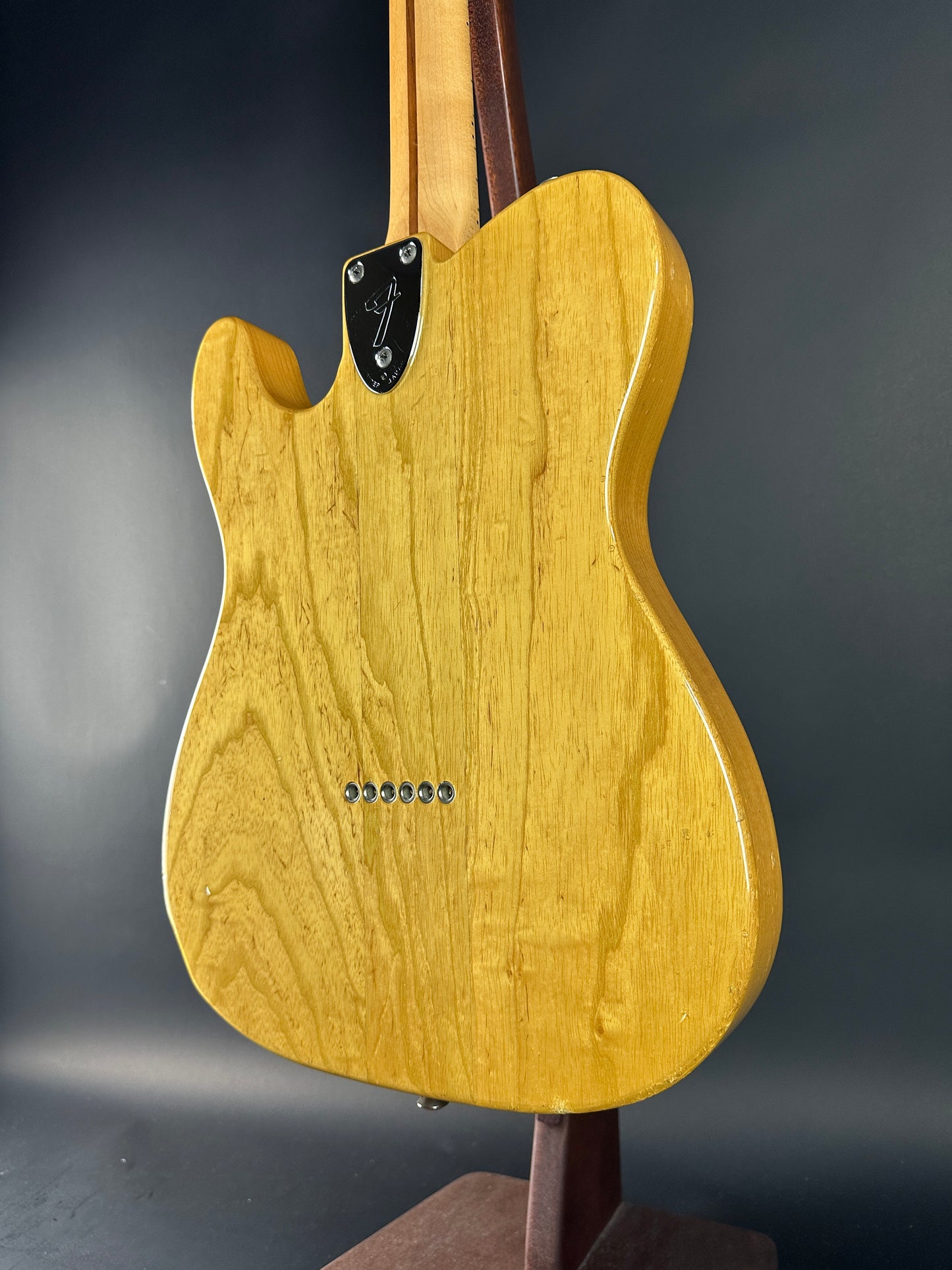 Wooden electric guitar body on a dark background