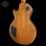 Close-up of a wooden electric guitar body with a visible brand logo on a black background.