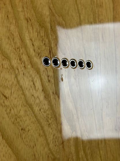 Close-up of a wooden surface with a metal bracket featuring five holes.