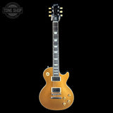 A gold-finish electric guitar, identified as a Gibson Les Paul Custom, is shown vertically against a solid black background. The headstock features the Gibson logo, and a 'TONE SHOP' watermark is visible in the top-left corner.