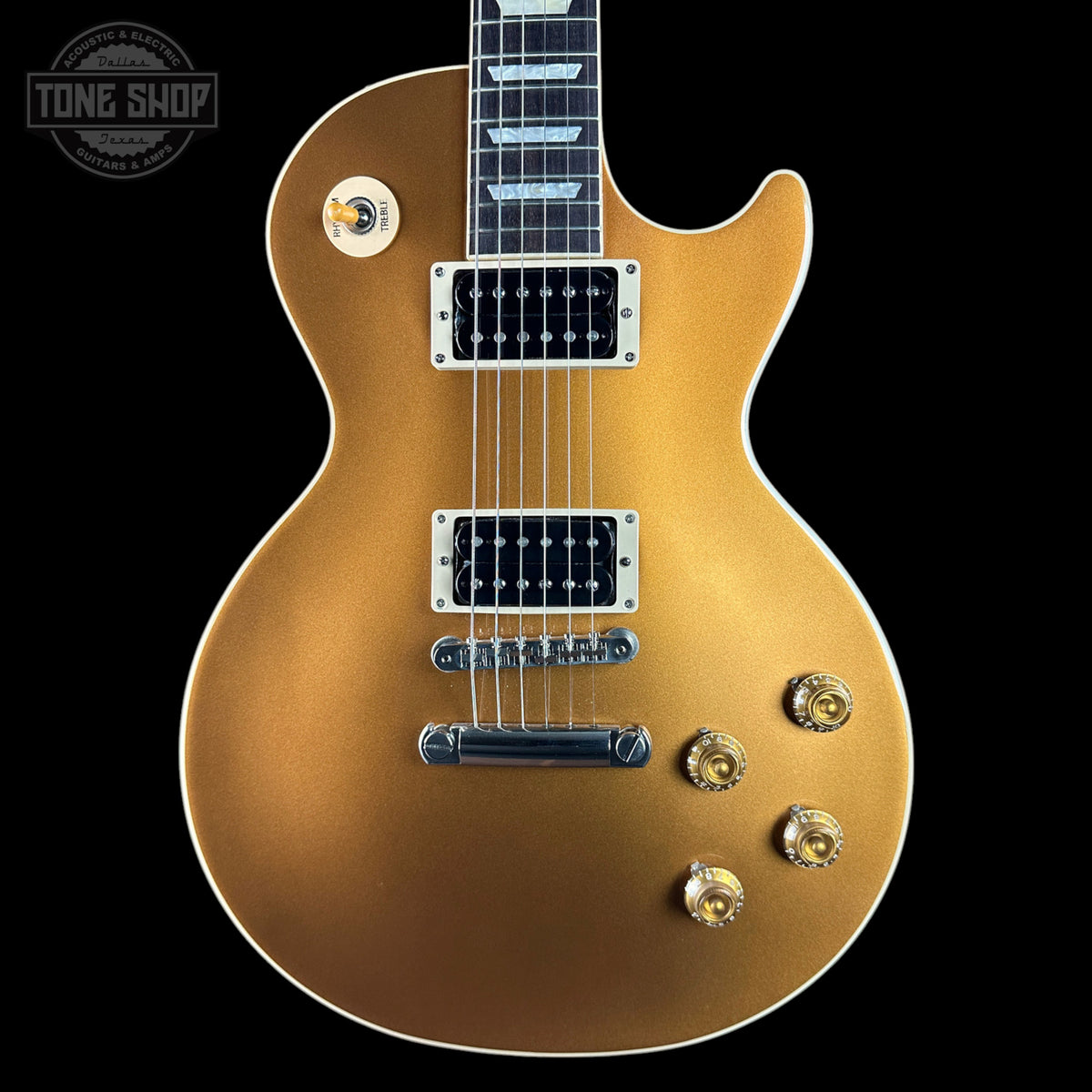 A gold-finish electric guitar with chrome hardware and black pickups, shown from the front against a solid black background. A Tone Shop watermark is visible in the top-left corner.